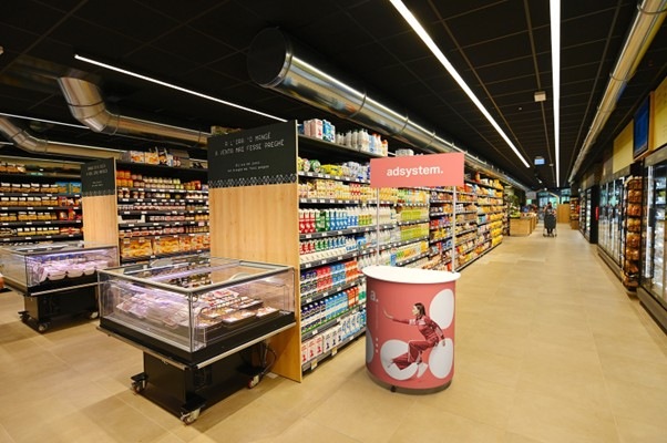 Mostrador para tienda con diseño publicitario rosa situado en un pasillo de supermercado